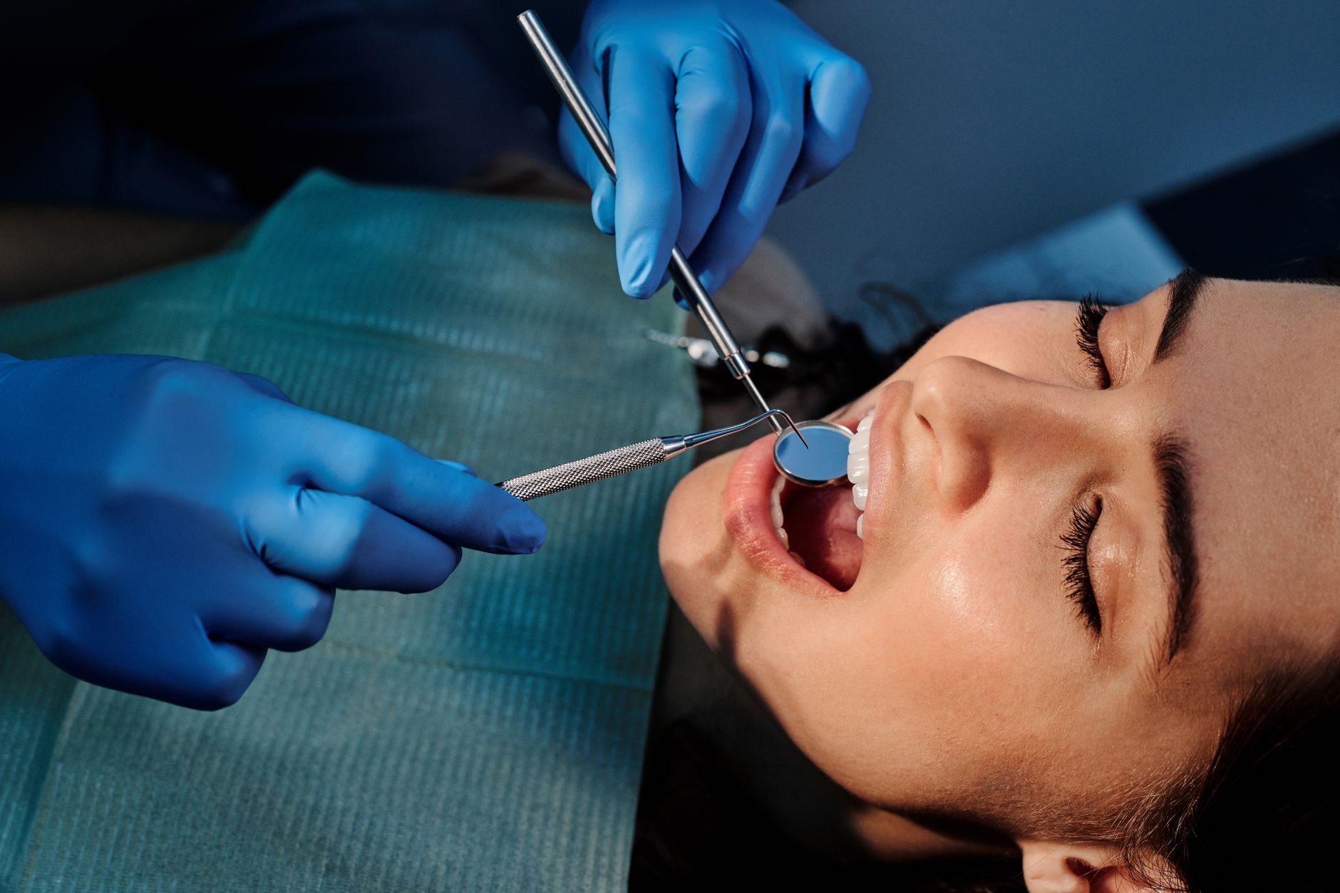 Close-up of a dentist examining a patient's teeth using dental tools. — Benefits of Scheduling Family Dental Appointments