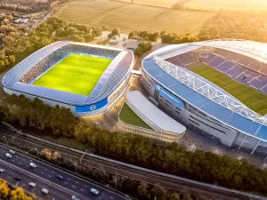 Aerial view of two soccer stadiums surrounded by green trees and a highway