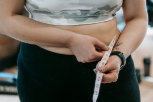 Crop anonymous plus size female with measuring tape measuring waist on blurred background — Can You Get Gastric Sleeve Twice?