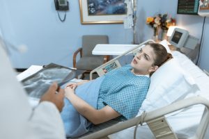 Caucasian woman in hospital bed receiving care from healthcare professional. — Dental Health Is Not Only About Your Mouth