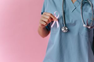 Healthcare worker in scrubs holds a pink breast cancer awareness ribbon symbolizing support. — Does Anthem Blue Cross Cover D