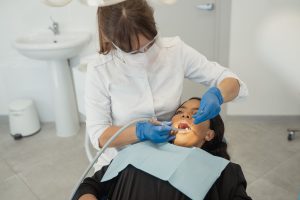 A female dentist wearing a facemask examines a patient's teeth in a dental clinic. — Does Full Coverage Dental Insurance Real