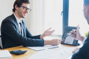 Two businessmen in formal attire discussing a business report in an office setting with a tablet. — Female Strength Unleashed
