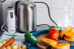 A vibrant array of fresh vegetables with a kettle and a blender on a kitchen countertop, ideal for healthy cooking. — Freeze