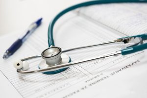 A stethoscope and pen resting on a medical report in a healthcare setting. — Get The Uncomfortable Experience With Taking The