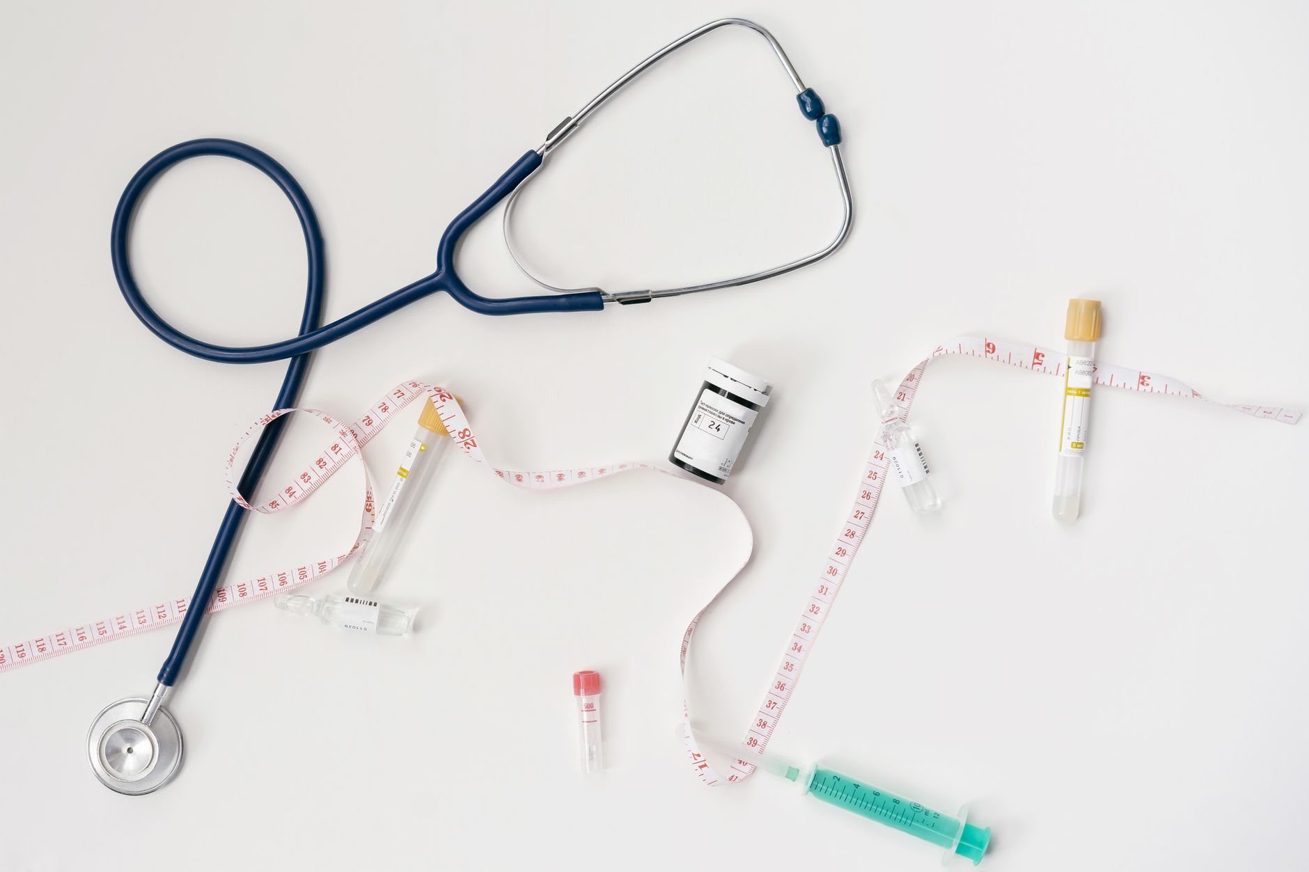 Top view of stethoscope, syringes, and tape measure on white background. — Health Insurance Rate Increases And Grandfathered