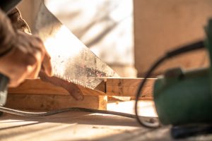 Carpenter cutting wood with a hand saw, showcasing craftsmanship and precision. — High-Quality Acoustic Panelling Offering Fu
