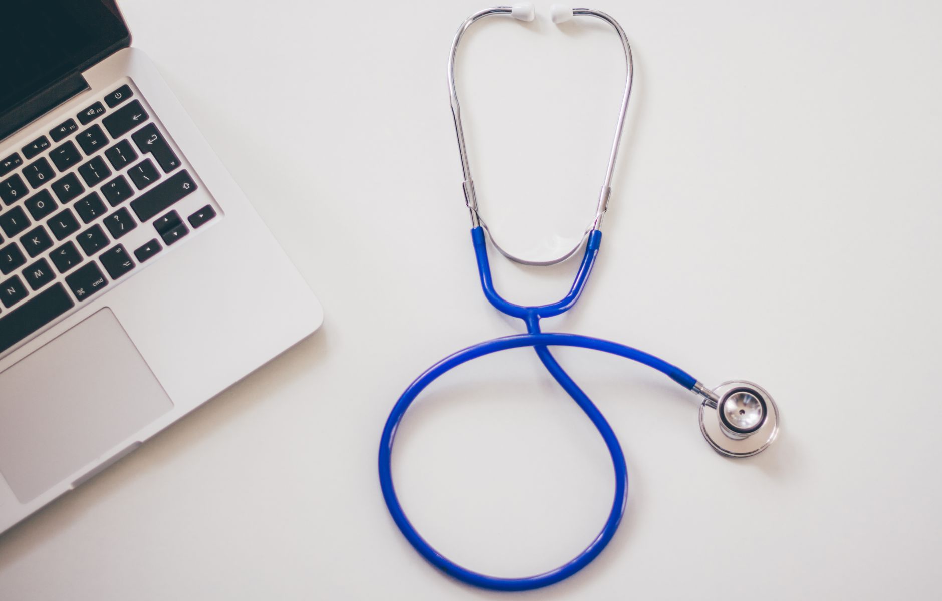 Medical stethoscope and laptop on a white desk, symbolizing digital health solutions. — How A Psychiatrist can Help with Your