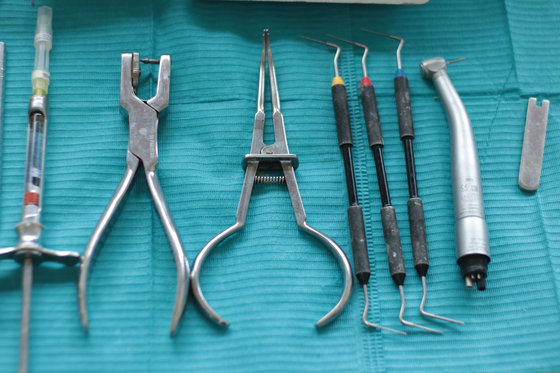 Close-up of dental tools on a teal cloth, including syringe, pliers — How To Tell Kids Not To Be Scared Of The Dentist
