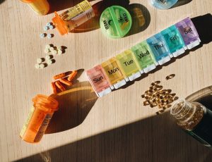Colorful pill organizer with medication bottles and tablets on a wooden surface. — Insights On The Latest Technologies Used B