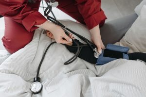A medical professional checking a patient's blood pressure using a sphygmomanometer in a cozy setting. — Isolate Protein's Si