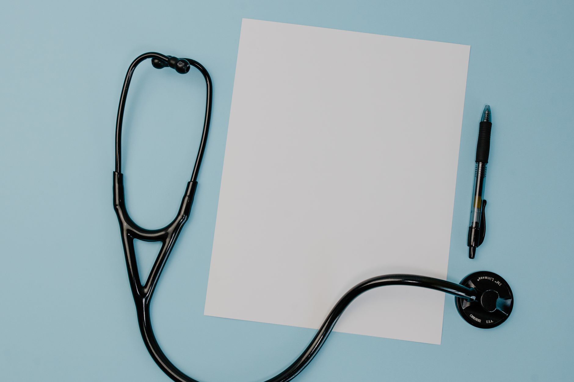 Flat lay of a stethoscope, blank paper, and pen on a blue background. — Some Vital Information For You To Know About Faking P