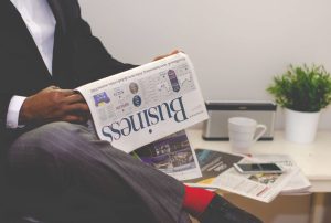 Businessman reading a financial newspaper at a desk, highlighting finance and commerce theme. — Buy Steroids in the U