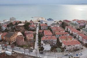 Aerial shot of a picturesque coastal town with red rooftops and a serene ocean view. — Learn More on Whey Isolate and