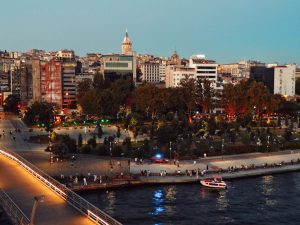 Scenic view of Istanbul's skyline featuring Galata Tower and bustling park at twilight along the waterfront. — STD Te