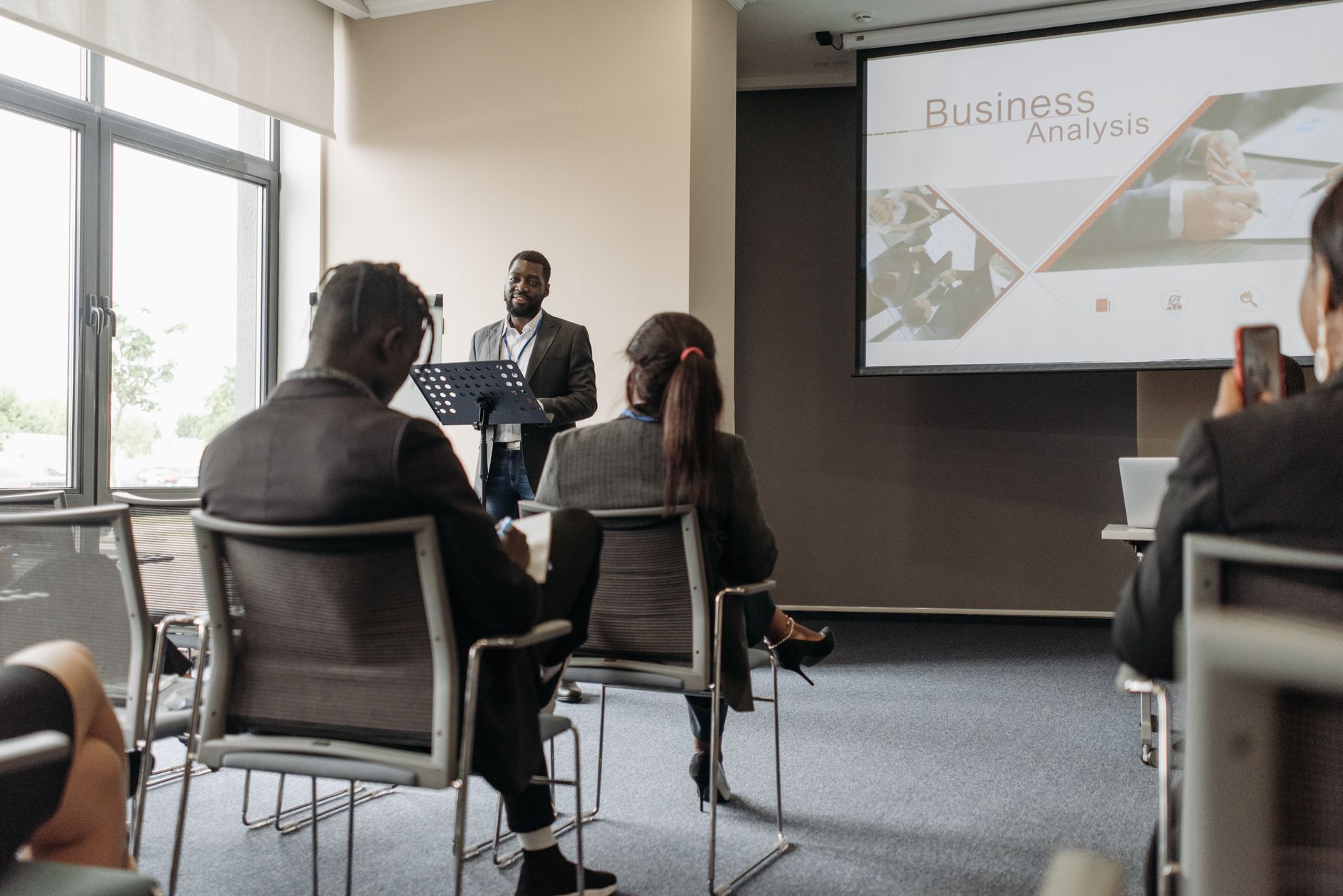 A business professional delivering a presentation in a conference room with diverse attendees. — UK Steroids Shops: E