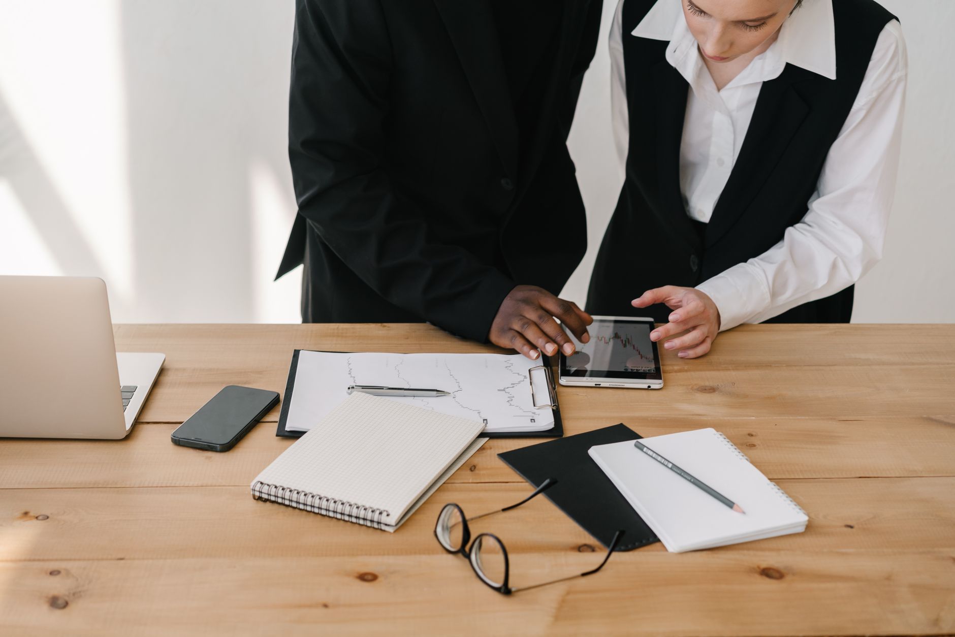 Two professionals collaborating over charts and tablet in a modern office setting. — Stuart Piltch AI: Empowering a Data-Driv