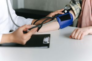 A healthcare worker uses a sphygmomanometer to check a patient's blood pressure in a medical office. — The Best Chiropractors