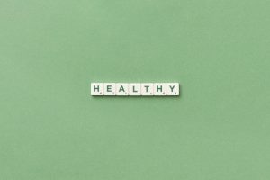 Scrabble tiles spelling the word 'healthy' on a light green background, top view. — Top Advantages Of Cycling