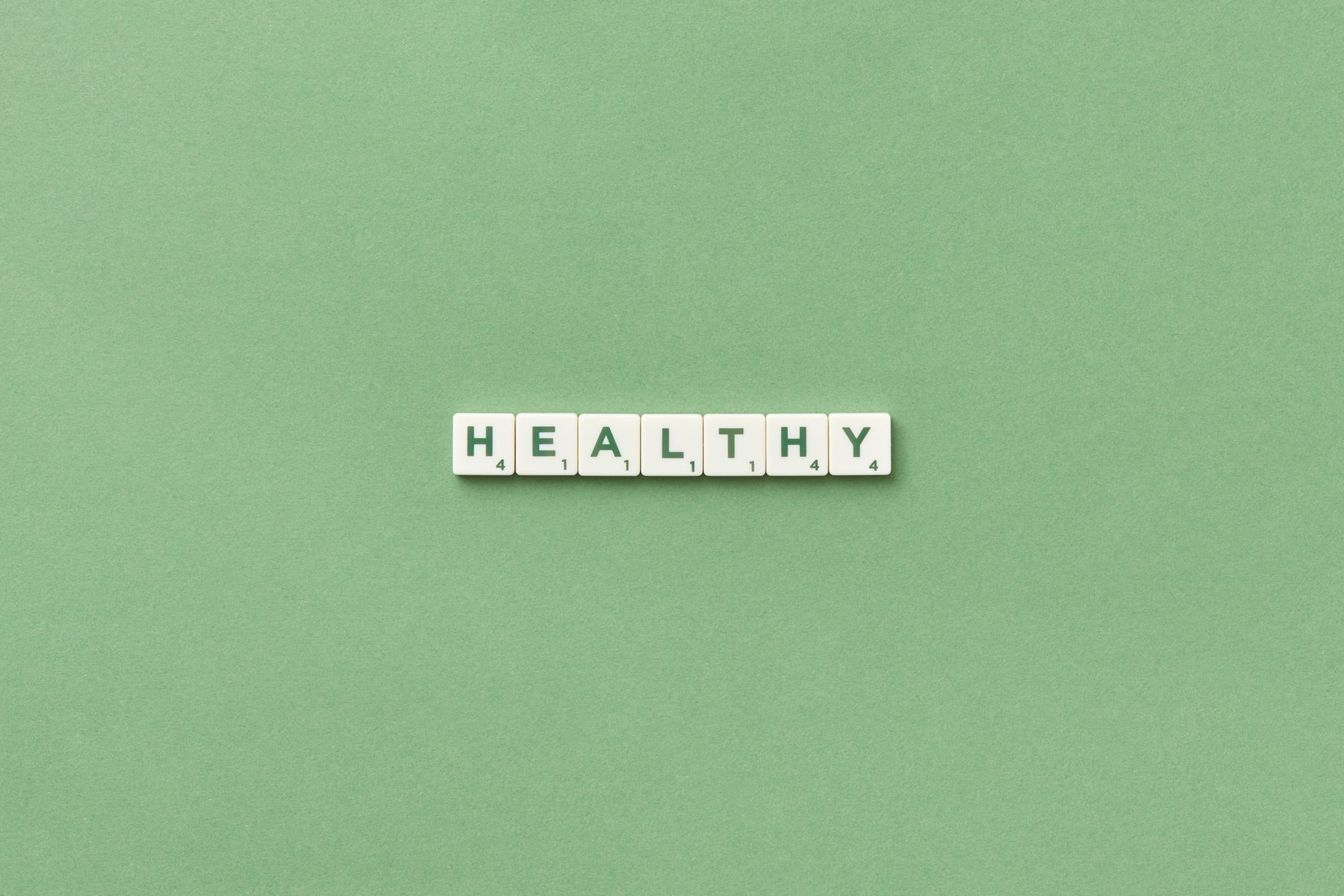 Scrabble tiles spelling the word 'healthy' on a light green background, top view. — Top Advantages Of Cycling