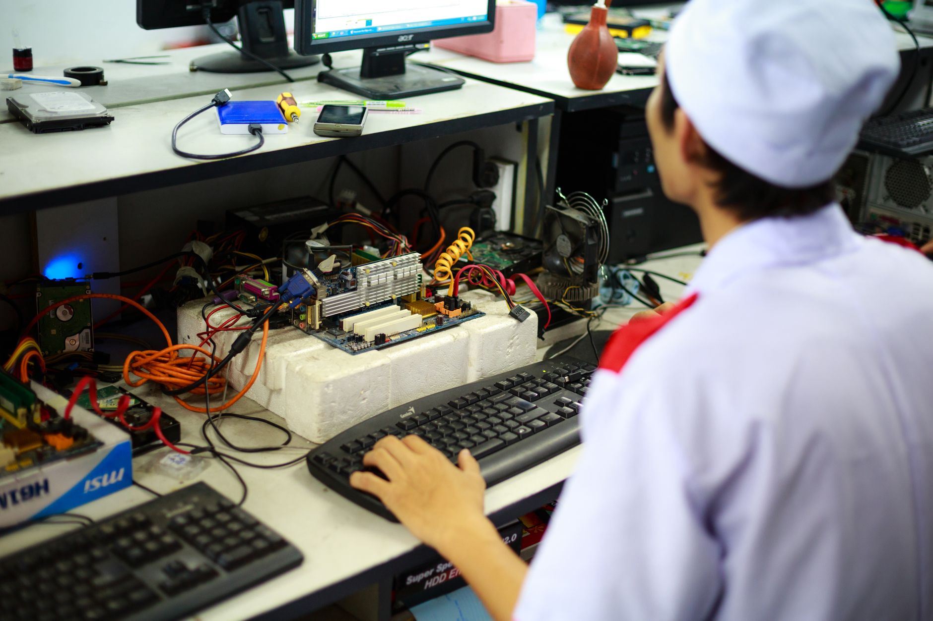 A technician in uniform working on a motherboard at a desk in a laboratory setting. — Web Design DC: Smart Solutions for Mode