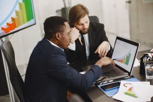 Two business professionals working on growth charts using laptop in an office setting. — Why Customer Communication Is Essent