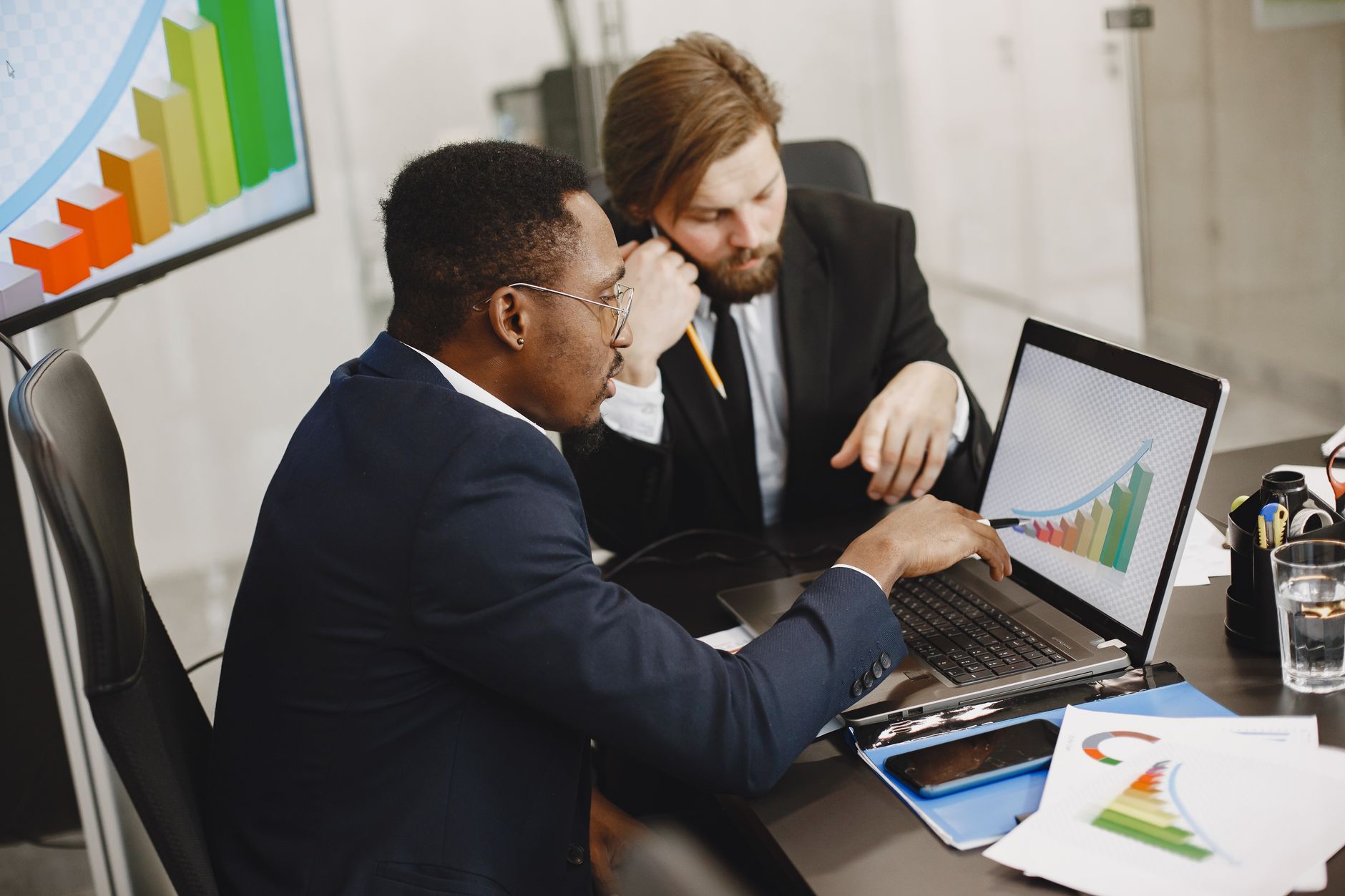 Two business professionals working on growth charts using laptop in an office setting. — Why Customer Communication Is Essent