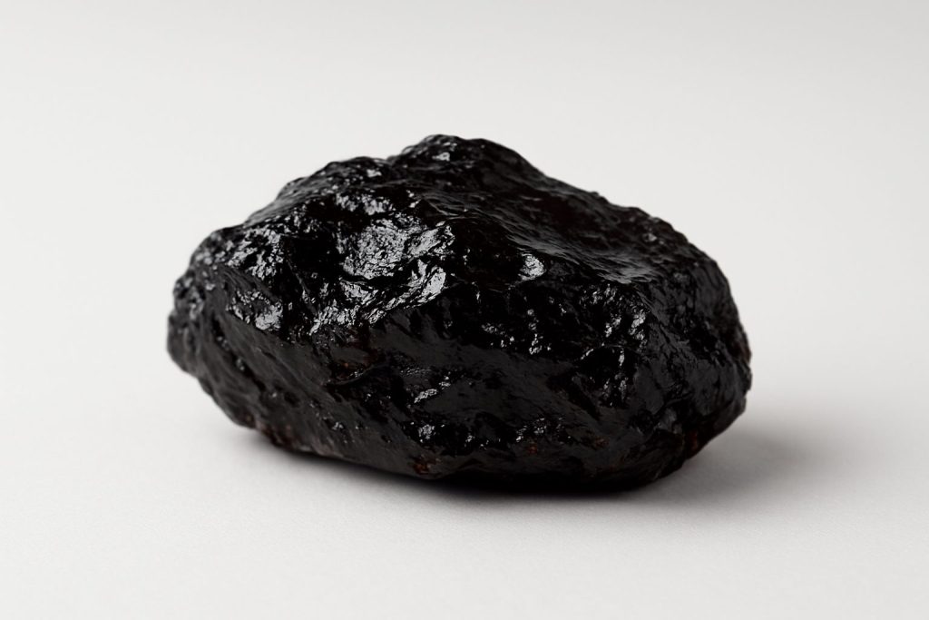 Close-up of a natural shilajit resin stone on a plain background