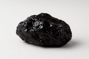 Close-up of a natural shilajit resin stone on a plain background